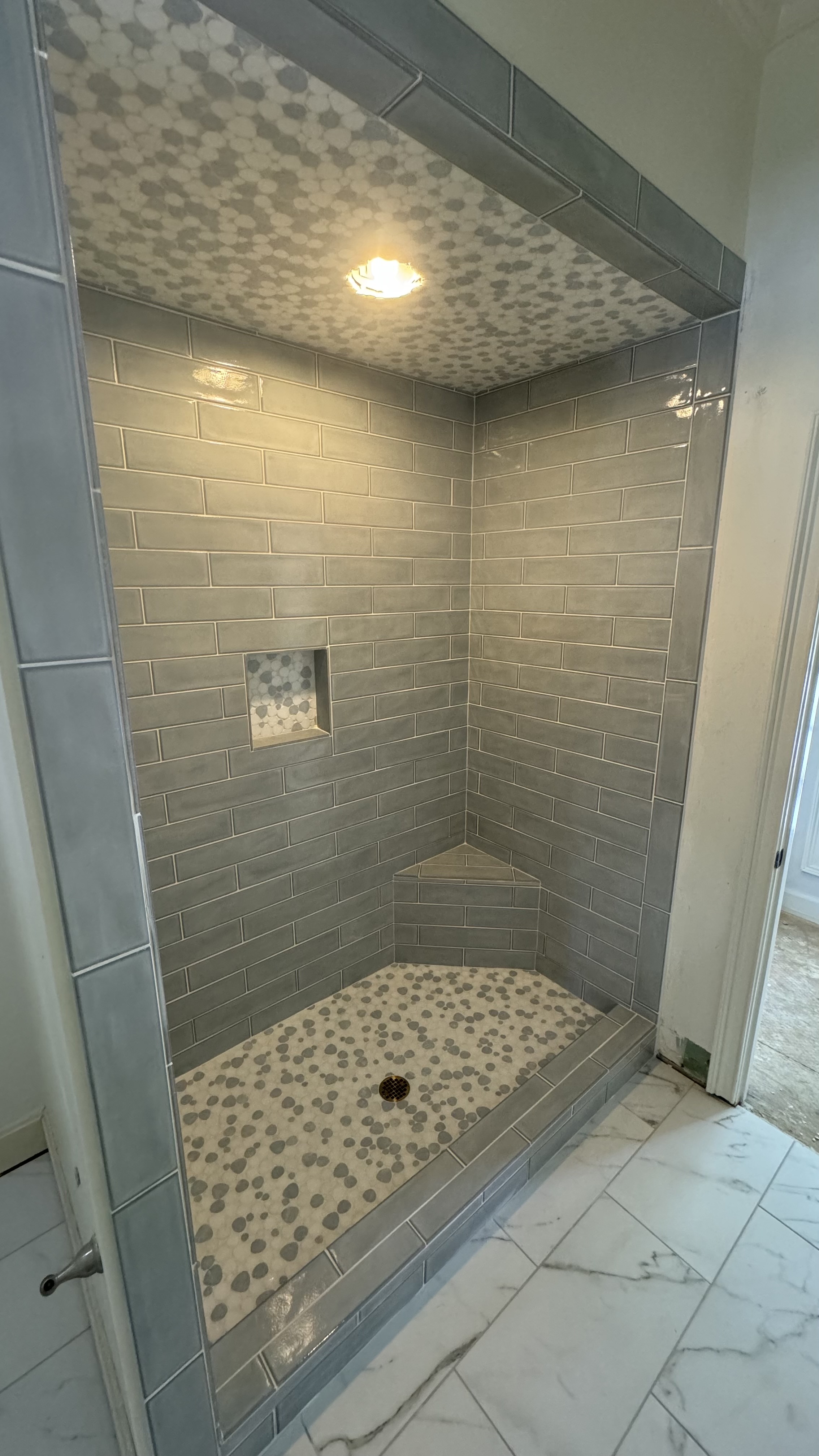 Custom gray tile shower with mosaic flooring