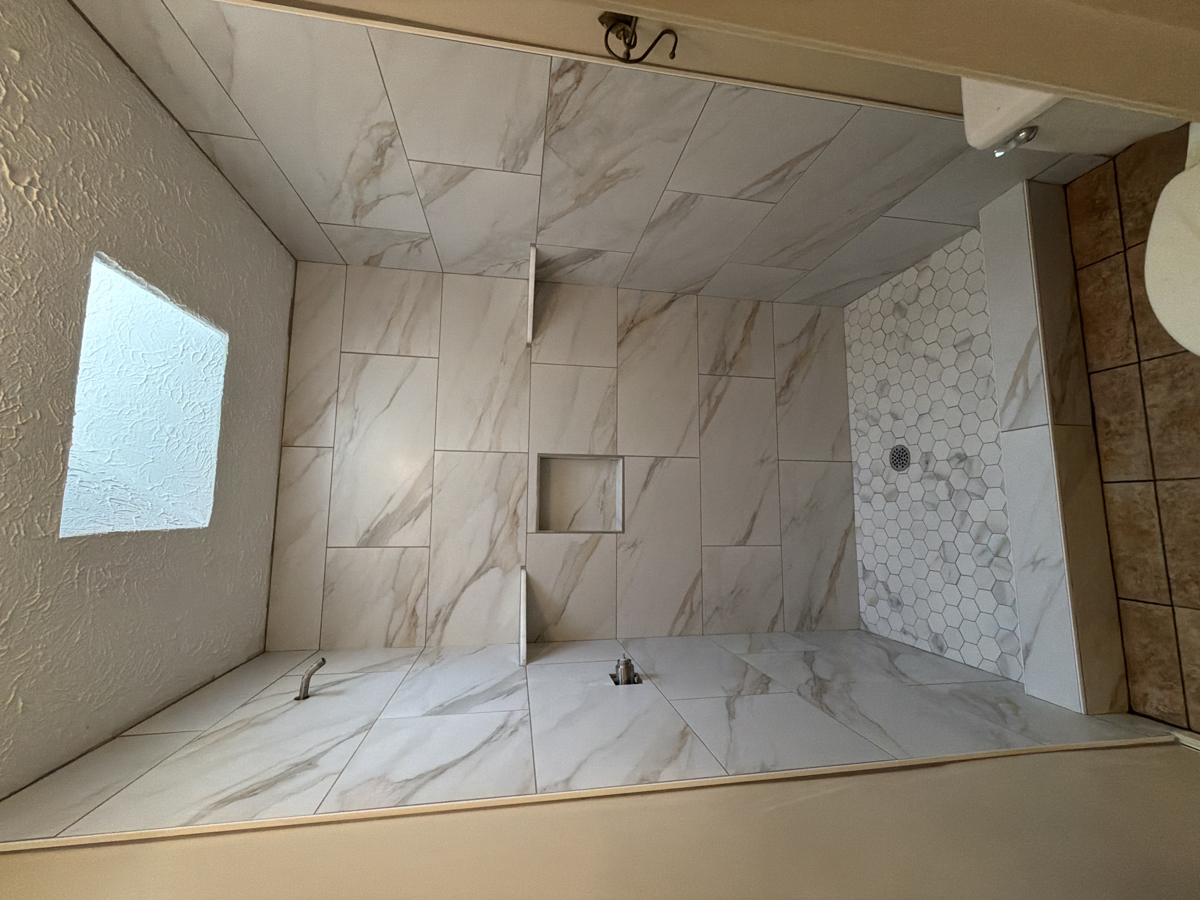 Marble tile shower with a white hexagon floor